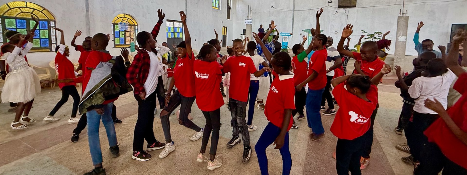 Young people in Redemptive Dance Ministries shirts worshipping through dance together inside a church, hands raised