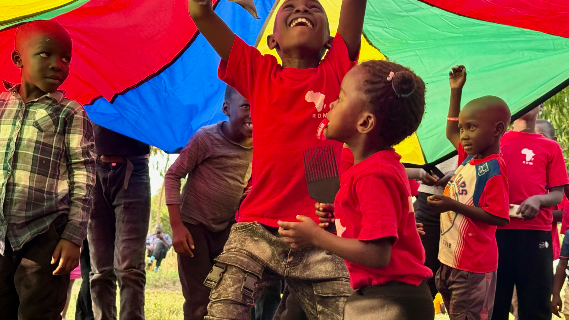 Children playing under a colorful parachute at a Redemptive Dance Ministries gathering in Kenya