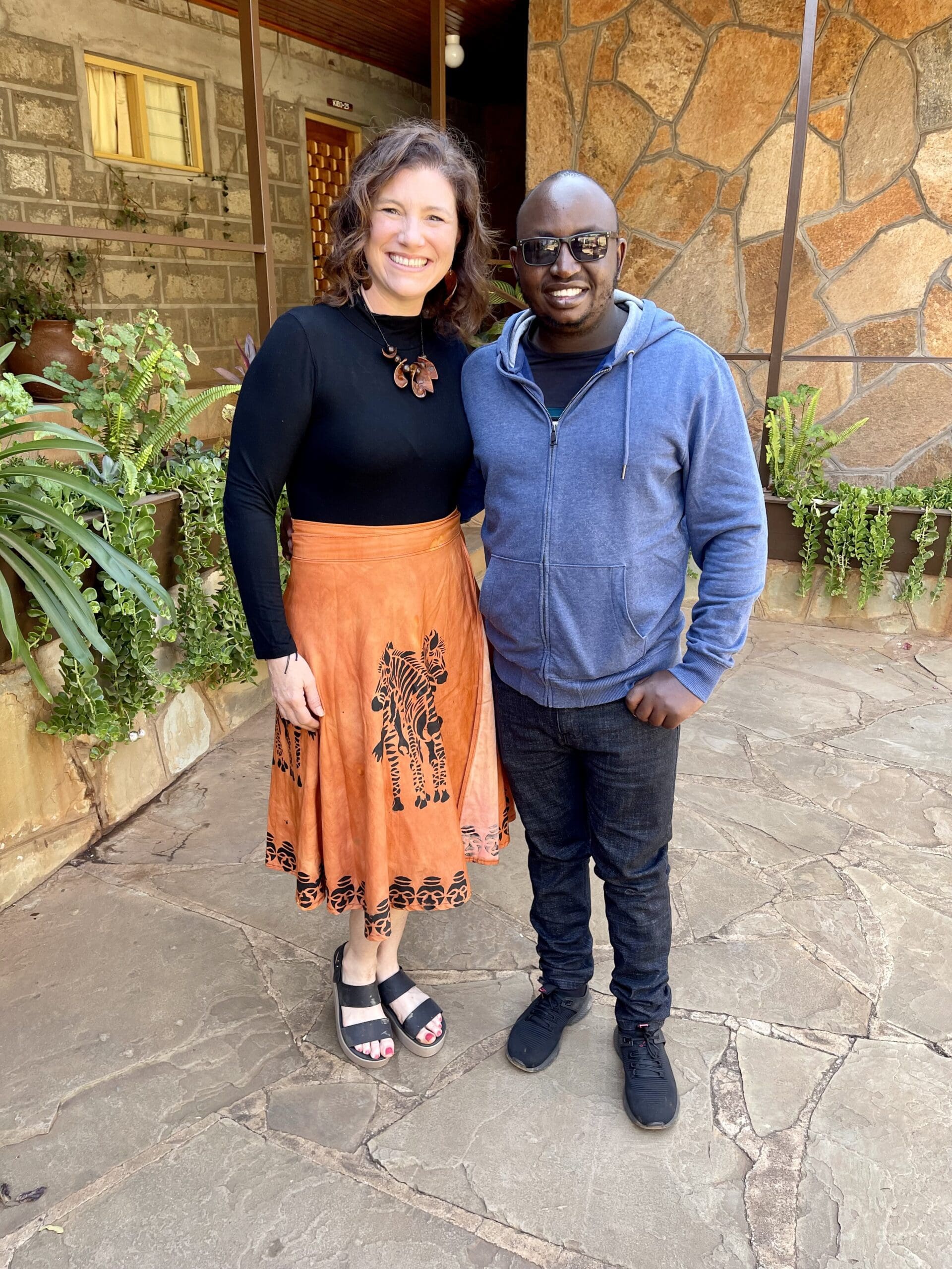 Heather Johnson, founder, smiling with a new team member outside the Kenya studio