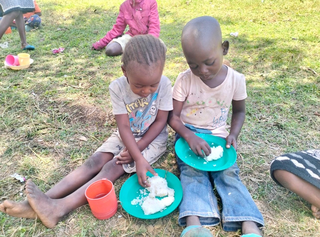 Children in Kenya enjoying a meal outdoors as part of the EmpowerDance Collective initiative by RDM, fostering community and support through dance.