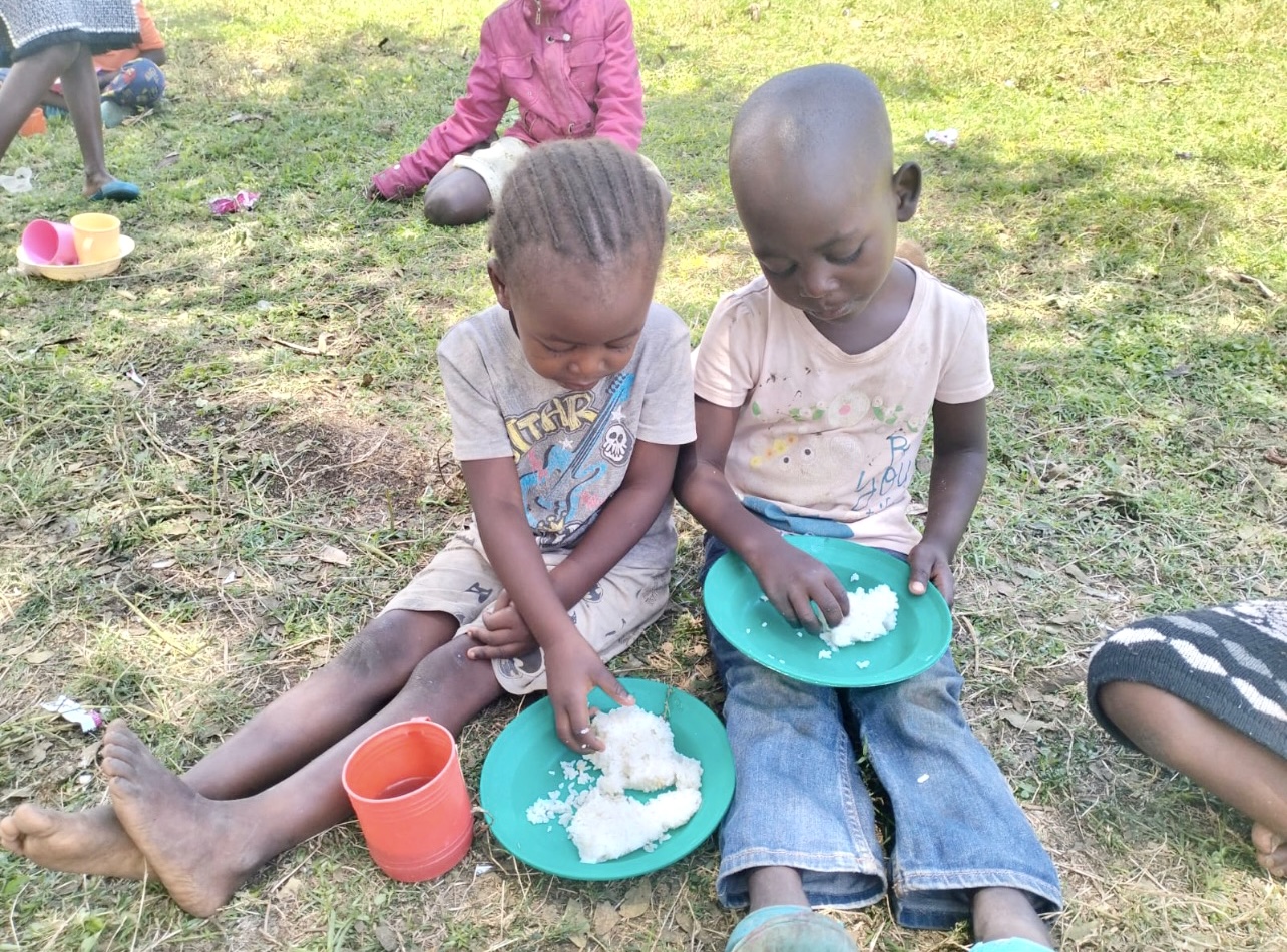 Children in Kenya enjoying a meal outdoors as part of the EmpowerDance Collective initiative by RDM, fostering community and support through dance.