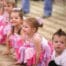 Excited young children in pink tutus lined up at a dance performance