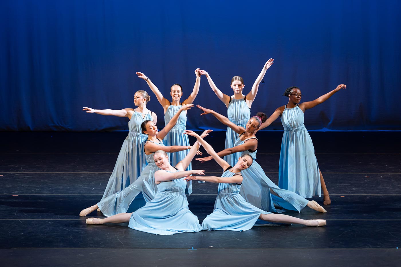 Ballet dancers in light blue dresses performing an elegant ensemble piece on stage